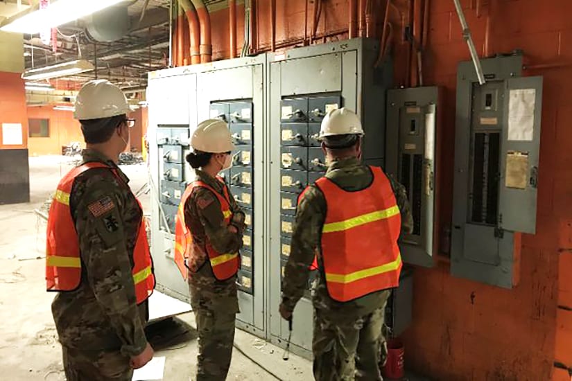 Ashley Anderson in Camouflage Uniform with two men, all in safety gear